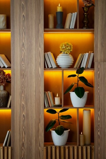 کتابخانه تزیین شده با نور مخفی بین طبقات، شمع و گلدان ها با گل های طبیعی 