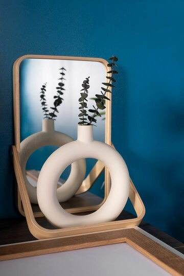 تصویر گلدان سرامیک سفید و مینیمال با طرح دایره و گل طبیعی داخل آن و آینه